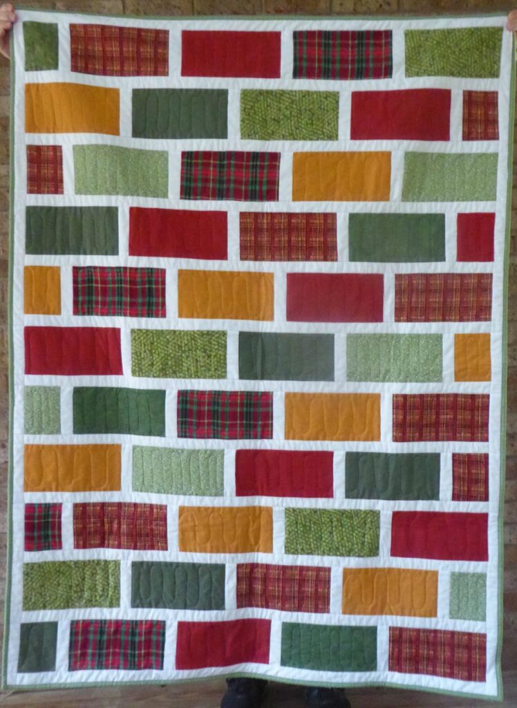 Quilt front - brick pattern with green, red and gold fabrics.